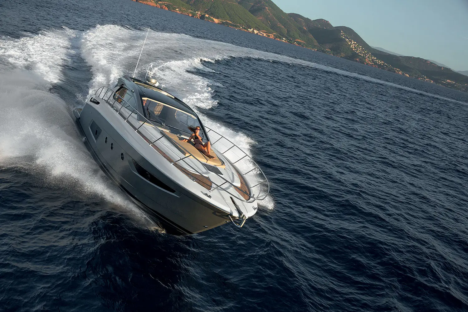 Dynamic luxury yacht sailing along the picturesque Adriatic Mediterranean coastline against sun-drenched coastal scenery