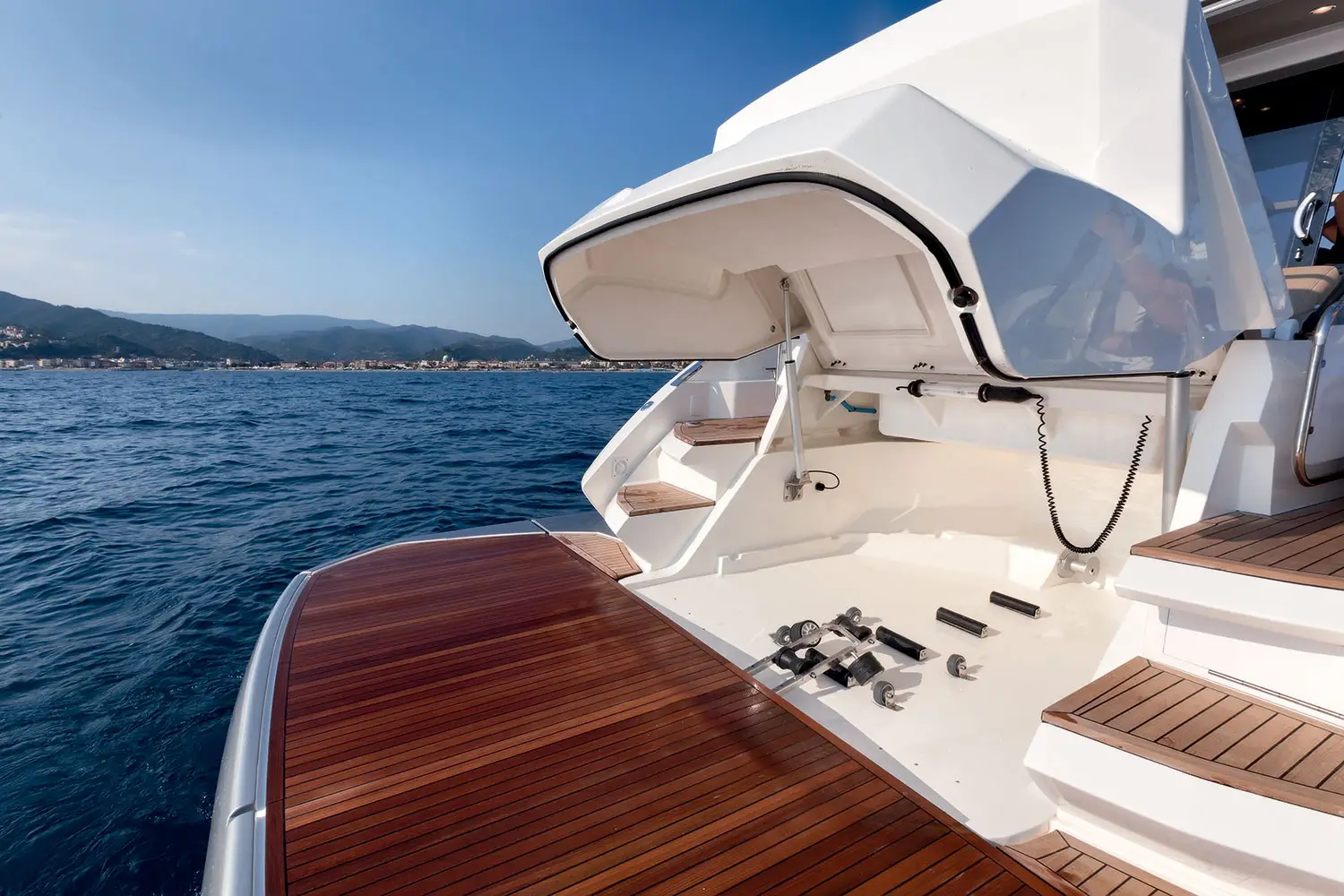 Moderne Motoryacht in Fahrt mit sonnenbadendem Gast auf dem Bugdeck bei einem exklusiven Tagescharter-Erlebnis